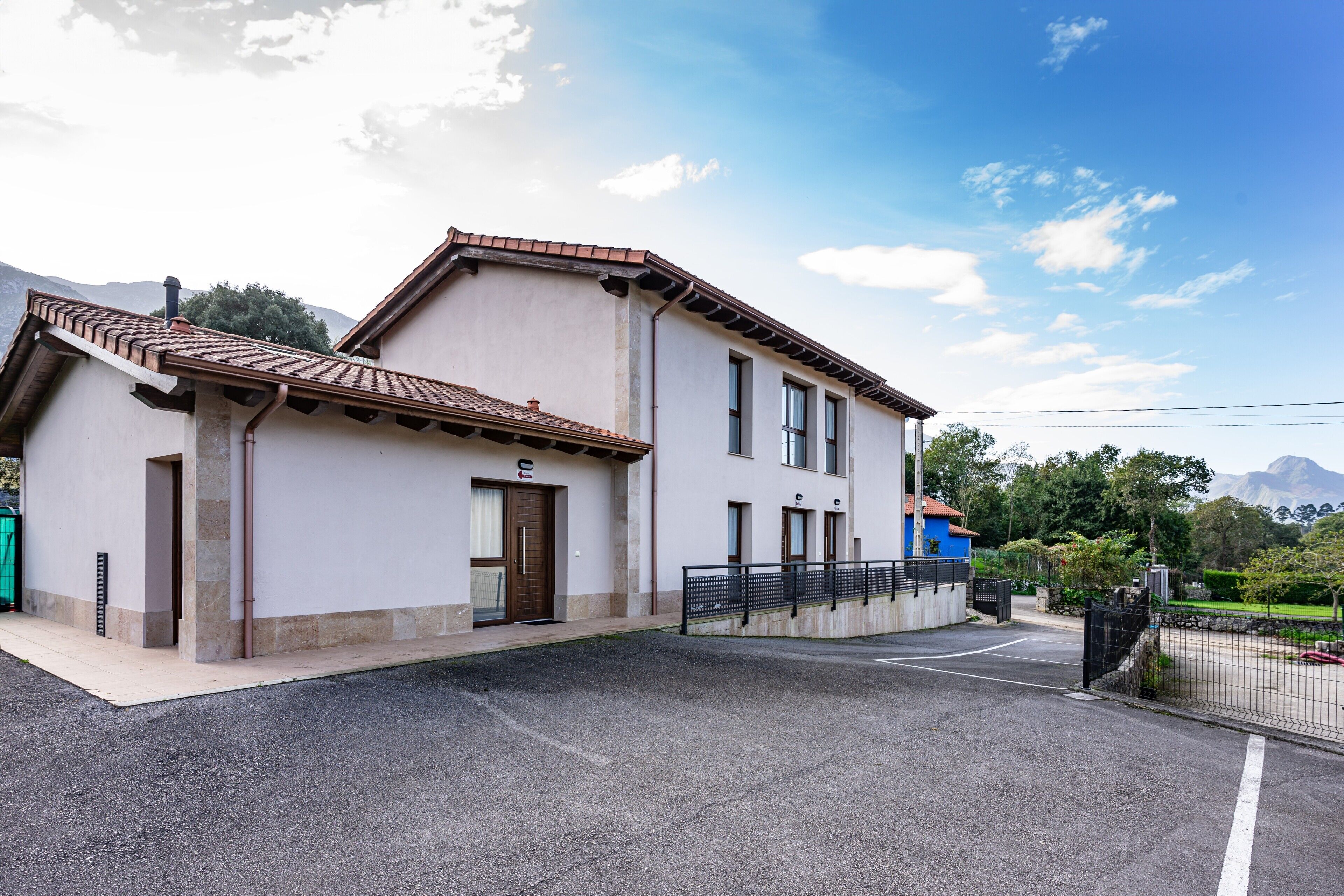 Un edificio a due piani con tetto in tegole, ingresso carrabile con cancello e vialetto lastricato.