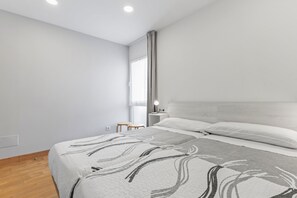 Une chambre à coucher moderne avec un lit, une table de chevet et une fenêtre avec des rideaux.