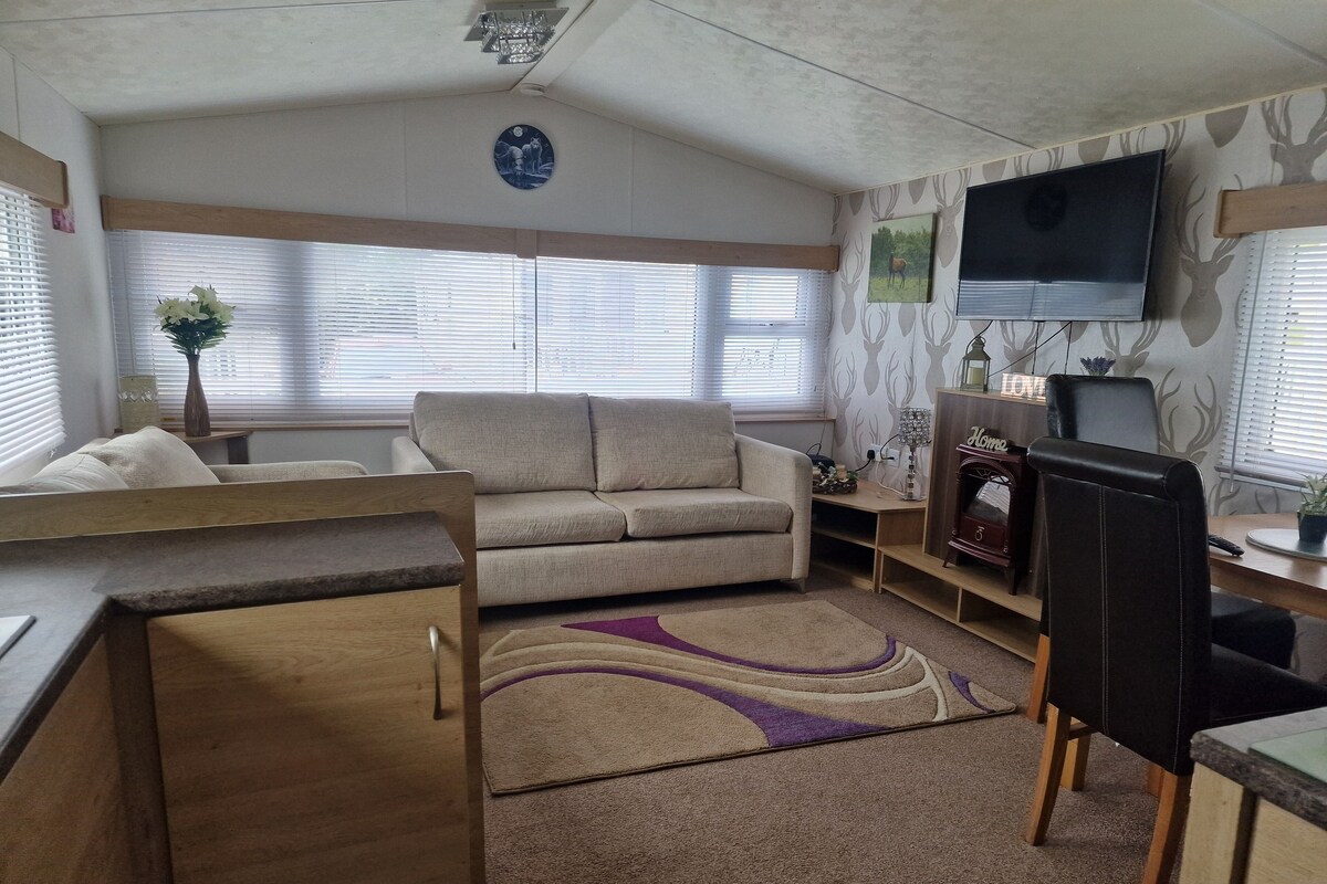 Un interno camper accogliente con un divano, un tavolo da pranzo, una TV a parete e un caminetto.