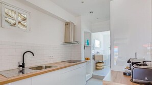 Een moderne keuken met witte kastjes, een houten aanrechtblad, een zwarte kraan en een inbouwoven.