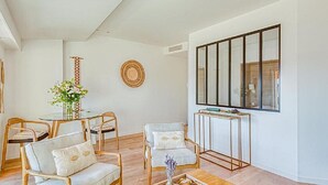 Een moderne woonkamer met een ronde tafel, twee fauteuils, een bank en een groot raam.