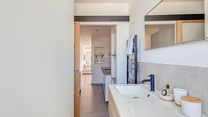 Een moderne badkamer met een groot wastafel, spiegel en douche.