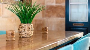 A polished wooden table with a woven plant pot, two small glass items, and a teal chair.