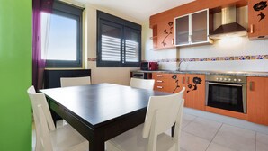 Una cocina moderna con armarios de madera, horno empotrado y comedor con mesa y sillas.