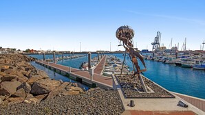 Marina con barcos amarrados, muelle y una escultura.