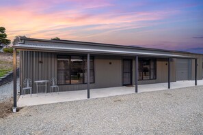 A modern building with a metal exterior, large windows, and a gravel driveway.