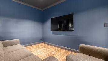 Ein Zimmer mit blauer Wand, Holzboden und zwei grauen Sesseln.