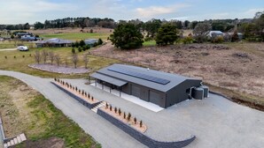 Un bâtiment moderne doté d’un toit plat, de panneaux solaires et d’une allée en gravier.