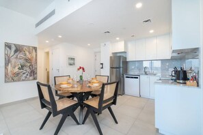 Una cocina moderna con armarios blancos, un refrigerador de acero inoxidable y un lavavajillas.
