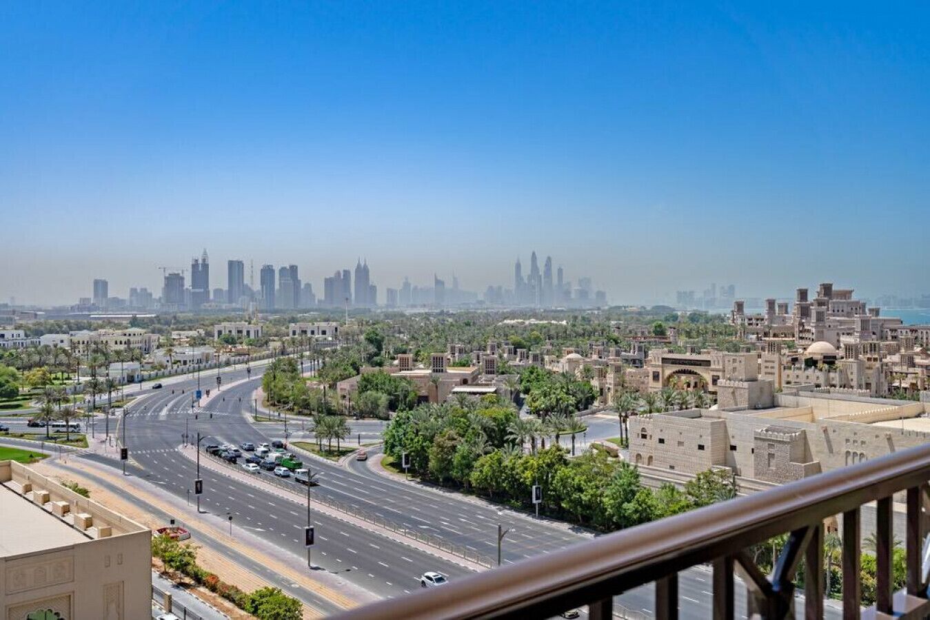 A cityscape with a prominent skyline, a wide road, and surrounding greenery.