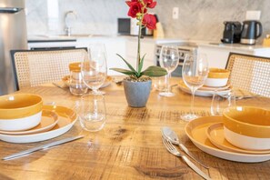 Una mesa de comedor dispuesta con cuencos amarillos, copas de vino y una planta en maceta.