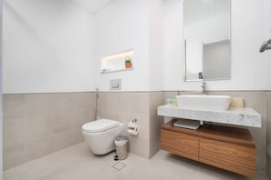 A modern bathroom with a toilet, sink, and mirror.
