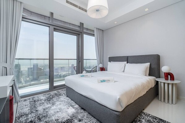 A modern hotel room with a large bed, a view of the city, and a balcony.