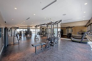 A modern gym with various exercise machines, a bench, and a treadmill.