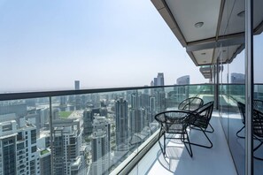 A high-rise balcony with a glass railing, offering a city view.