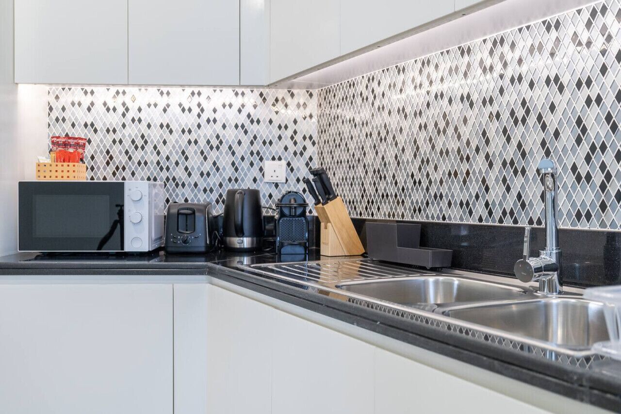 A modern kitchen with a microwave, toaster, coffee maker, and knife block on the counter.