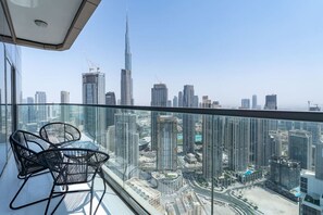 Un balcon situé dans un immeuble de grande hauteur, offrant une vue sur la ville, avec des bâtiments modernes et un ciel dégagé.