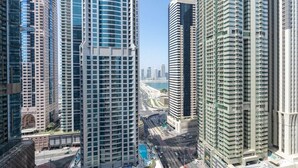 Un quartier urbain dense, avec de hauts gratte-ciel modernes, une rue animée et un ciel dégagé.