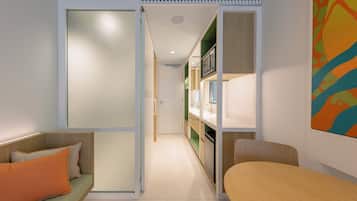 Un espacio habitable moderno y funcional con sofá, mesa de comedor y zona de cocina.