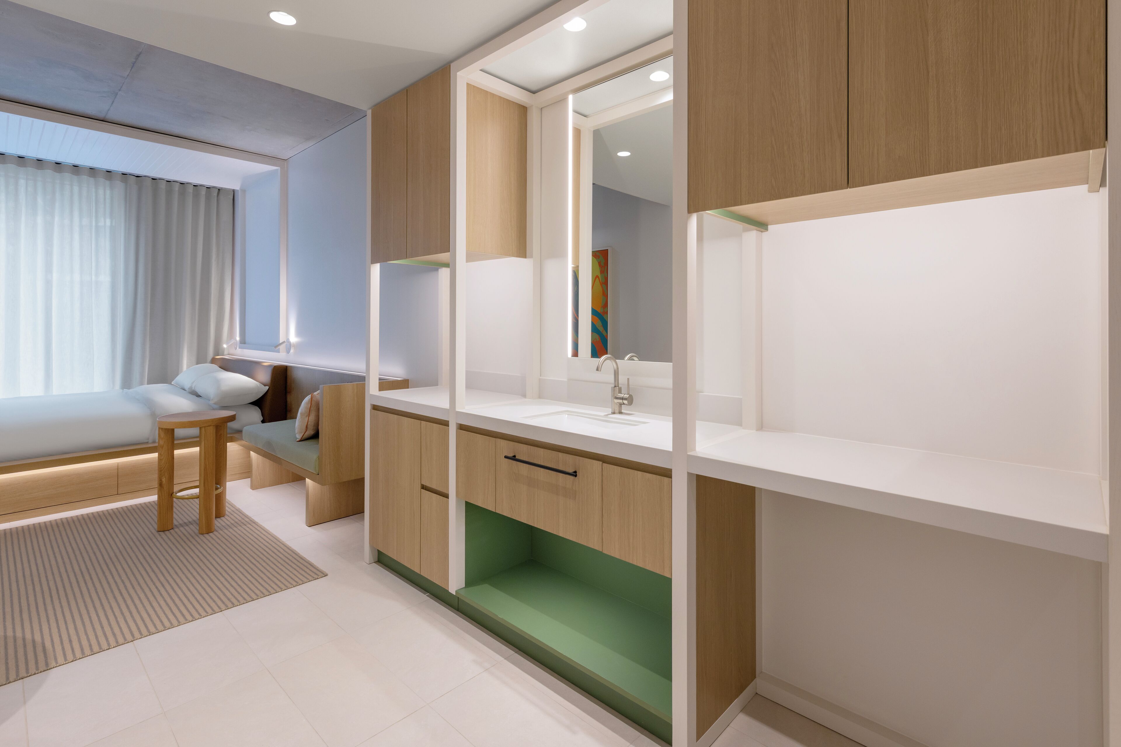 A modern bedroom with a bed, bedside table, and a large mirror.