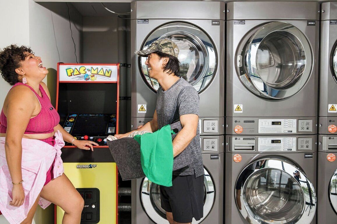 A laundromat with multiple washing machines and a Pac-Man arcade game.