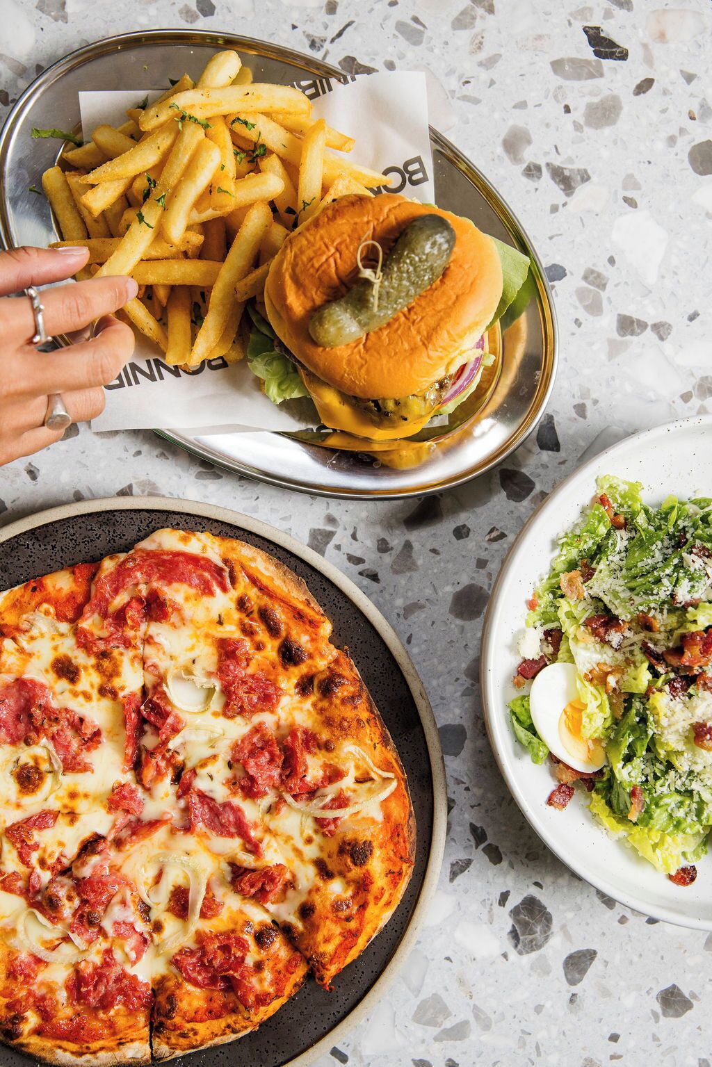 A meal consisting of a burger, fries, a pizza, and a salad.