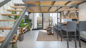 Un espace de vie moderne comprenant un escalier, un coin salon et un bureau avec un ordinateur portable.