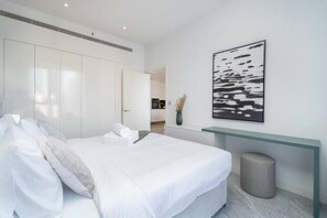 A modern bedroom with a large bed, a glass console table, a grey waste bin, and a black and white abstract painting on the wall. - The Pad 1109 - Business Bay · Cosmopolitan Apartment with Burj Khalifa View (Dubai)