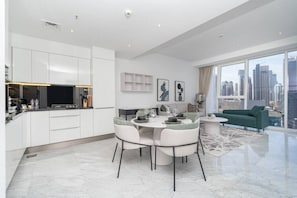 A modern living room with a dining area, a sofa, and a city view. - The Pad 1109 - Business Bay · Cosmopolitan Apartment with Burj Khalifa View (Dubai)