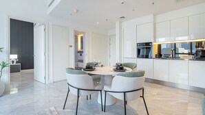 A modern kitchen with white cabinets, a dining area with a round table and chairs, and a visible oven and microwave. - The Pad 1109 - Business Bay · Cosmopolitan Apartment with Burj Khalifa View (Dubai)