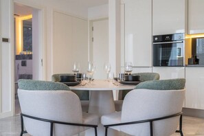 Ein moderner Essbereich mit einem runden Tisch, gedeckt für vier Personen, umgeben von gepolsterten Stühlen mit grünen Akzenten.