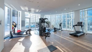 A spacious gym with various exercise equipment, large windows, and a modern design.