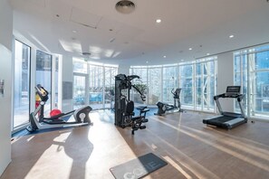 Un gimnasio amplio con diversos equipos de ejercicio, ventanas grandes y un diseño moderno.