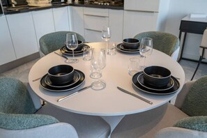 A round dining table set with black plates, clear glasses, and cutlery. - The Pad 1109 - Business Bay · Cosmopolitan Apartment with Burj Khalifa View (Dubai)