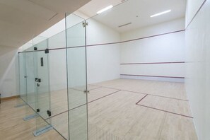 A squash court with glass walls and a wooden floor.