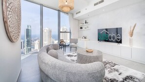 A modern living room with a large window, a sofa, a round coffee table, and a TV displaying 'suiteable'.