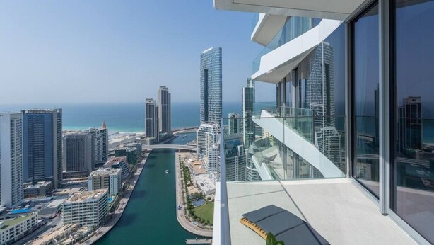 A high-rise building with a view of a coastal cityscape, including a marina and several other tall buildings.