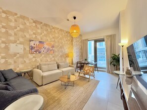 A modern living room with a sofa, armchair, coffee table, and a dining area with a table and chairs.