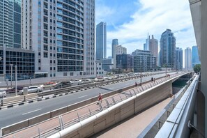 A modern urban street with high-rise buildings, a pedestrian walkway, and a clear sky.