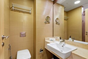 A bathroom with a toilet, a sink, a mirror, and a towel rack.