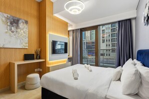 Une chambre d’hôtel moderne avec un grand lit, une télévision, un bureau et une vue sur la ville.