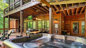 Una cabaña de madera con hidromasaje, mobiliario exterior y una terraza.
