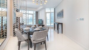 Un comedor moderno con un panel de vidrio, una araña y vistas a la ciudad.