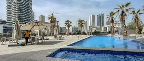 A rooftop pool area with a clear view of surrounding high-rise buildings and palm trees.