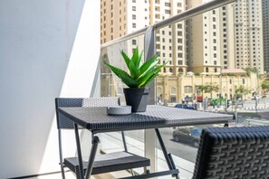 Un balcon avec une petite table, un pot de fleurs et une chaise.