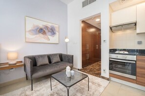 Uma sala de estar moderna com um sofá cinza, uma mesa de centro de vidro e um quadro na parede.