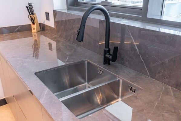 Una cocina moderna con un lavamanos de acero inoxidable, un grifo negro y un bloque para cuchillos.