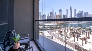 A balcony with a view of a city skyline, including a tall building and a marina. - 15 Northside - 210A · Contemporary Ranch Living with Burj Khalifa View (Dubai)