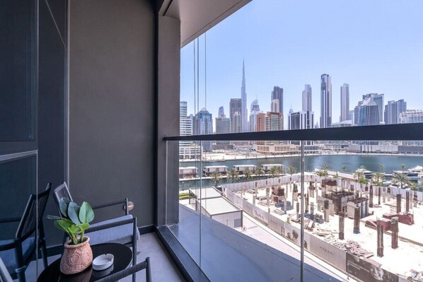 A balcony with a view of a city skyline, including a tall building and a marina.