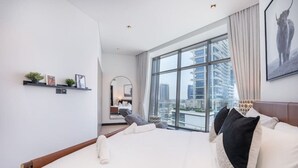 A modern hotel room with a large bed, a city view, a small seating area, and a large window. - 15 Northside - 210A · Contemporary Ranch Living with Burj Khalifa View (Dubai)